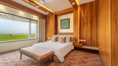 A double bed with a painting hung above in the Suite - Shyama Sarovar Portico Orai