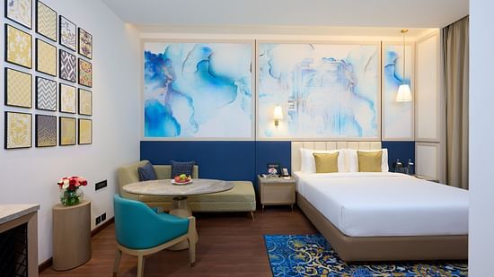 An image of a hotel bedroom in Amritsar with artistic wall papers, cosy furniture, warm lighting and a plush bed - Sarovar Premiere Amritsar