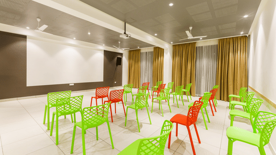Entertainment Room with green and red plastic chairs facing a wall with a projector screen at The Residences at CSE.