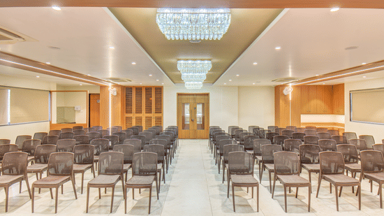 Ballroom at VITS Select Nashik Hotels & Resorts featuring chairs lined up under warm lighting and a door in the background