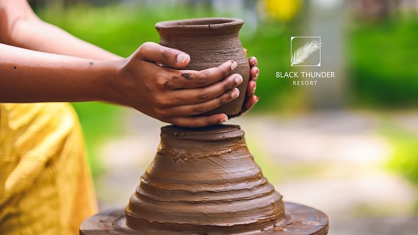 A close-up of hands shaping clay on a potter's wheel, highlighting the creative process of pottery-making - Black Thunder, Coimbatore