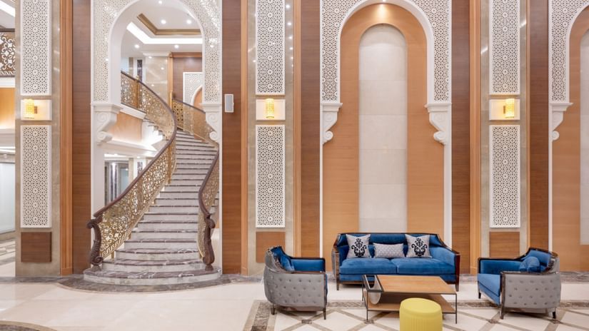 lobby area with sofas and a coffee table next to a staircase - La Maison Hotel, Doha