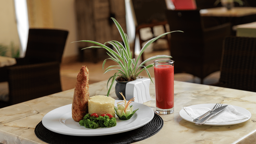 Plated main course with fresh juice served on a marble table in the restaurant at The Heron Nairobi