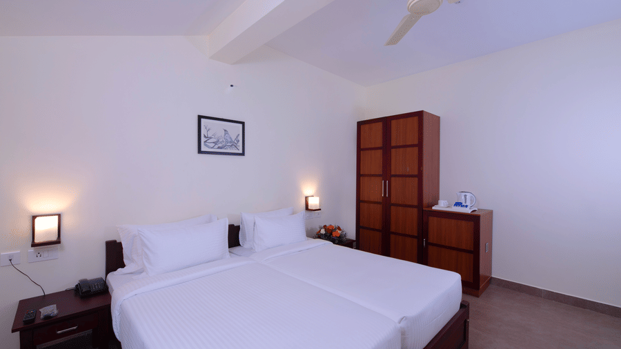 A bedroom features a bed, artwork on the wall, and a lamp.