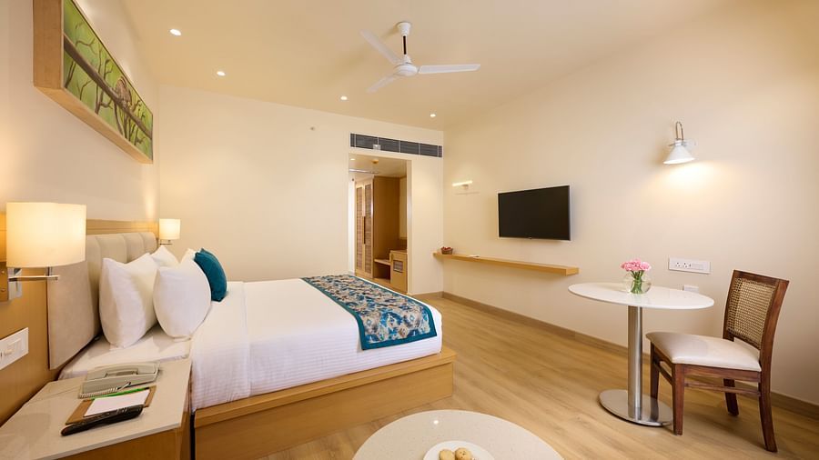 a double bed, television, table and chair in the Deluxe room at ABN Sarovar Portico, Jim Corbett
