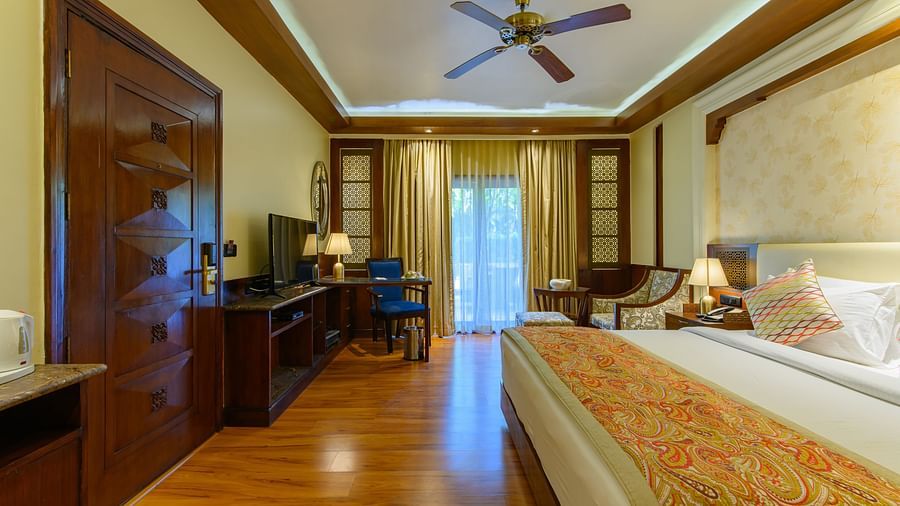 The interiors of our Premium Cottages in Pushkar featuring a balcony, a comfotable bed, sofa chairs 162 159