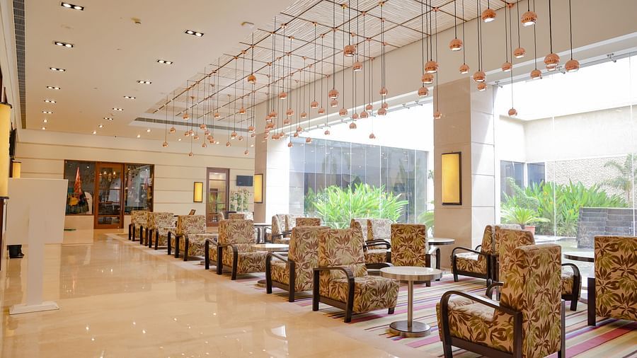 An inviting tea lounge with green armchairs, wooden tables, and soft lighting - Balaji Sarovar Premiere, Solapur