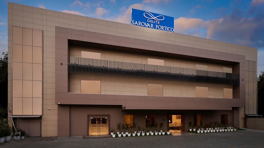 A facade image of a hotel with a sign board of the hotel name on the top