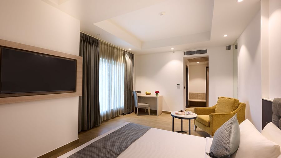 A hotel room with a large bed placed in front of a wall-mounted television
