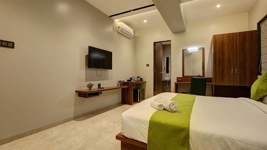 A double bed with a tv wall mounted opposite it inside Classic AC Room - Fortune House, Magarpatta