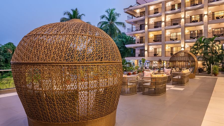 Outdoor lounge setup with wicker dome seating and hotel building in the background - Golden Tulip, Candolim, Goa