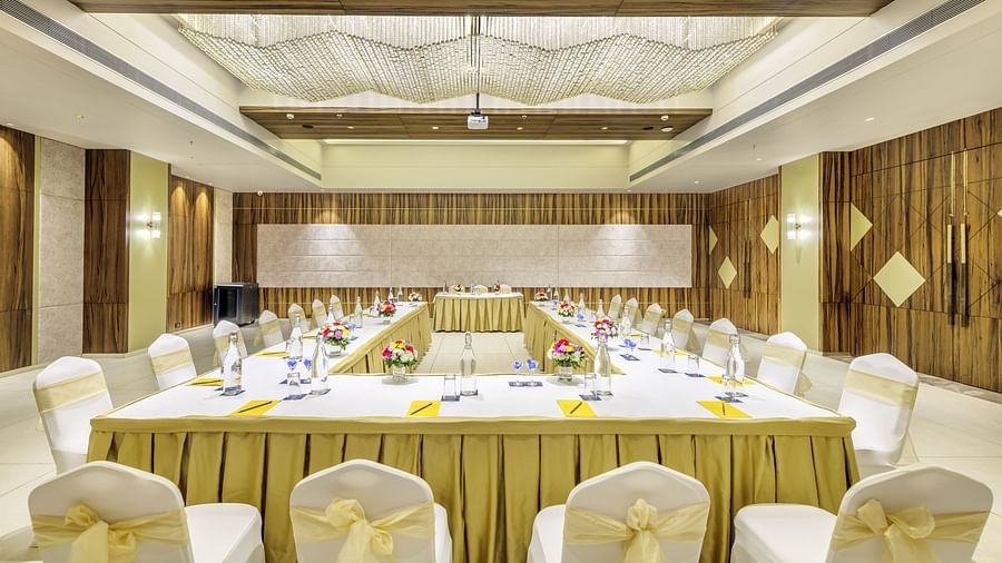 Well-lit banquet hall at the Golden Tulip, Candolim, Goa, decorated with golden drapes and elegant seating for an event.