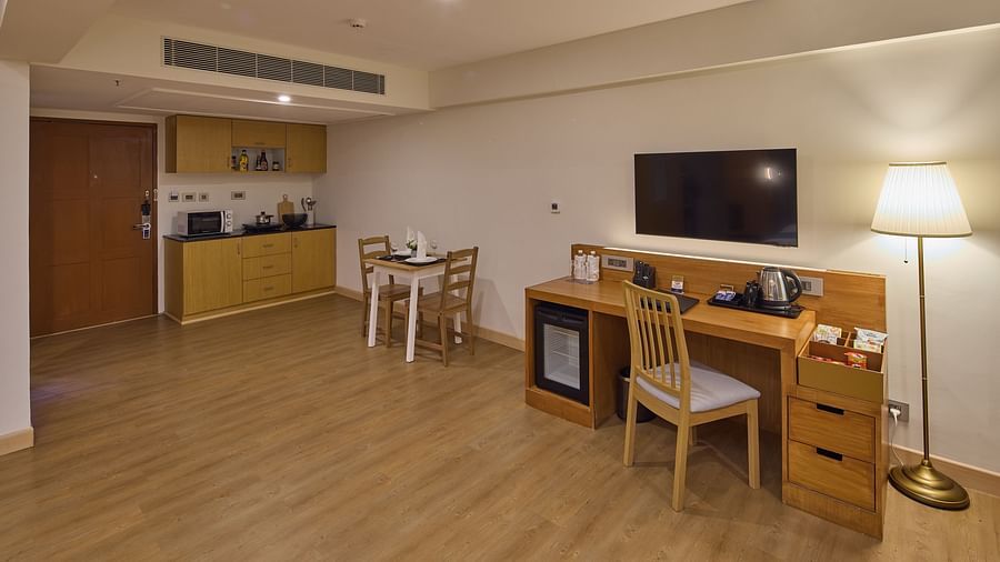the kitchenette, dining table, desk, chair and television in The Grand Suite Sea View at Grand Continent, Mahabalipuram