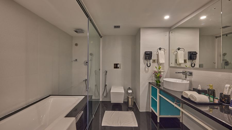 a bathtub with shower, a water closet, and a vanity area in the bathroom in a Grand Suite Sea View at Grand Continent, Mahabalipuram