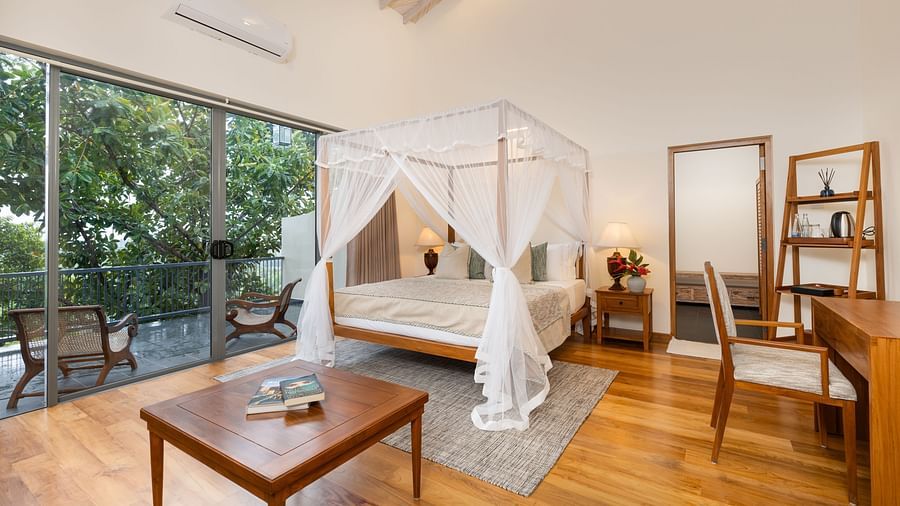 A luxurious bedroom with a canopy bed, a sitting area, and a private balcony overlooking the lush greenery - Suite with Private Pool at Heavensa Villas and Suites by the Clarks, Galle