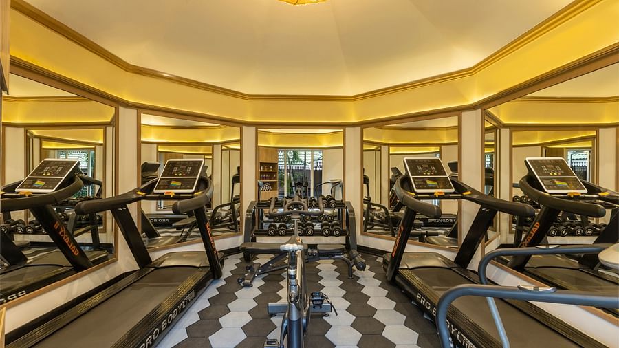 Modern resort gym with treadmills and a mirrored wall in a well-lit fitness room.