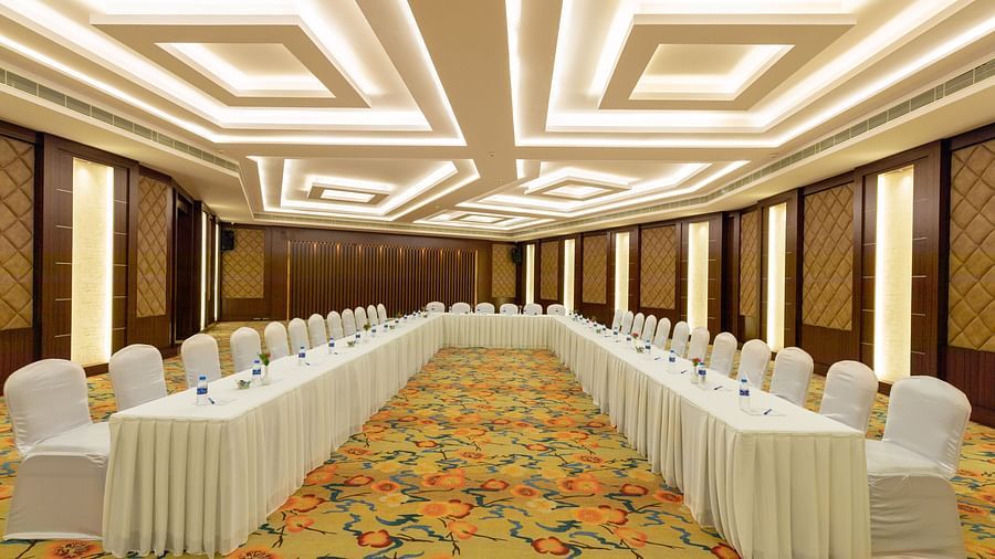 Elegant Jade Room with U-shaped table arrangement and chairs. The room features patterned carpet, wood-paneled walls, and bright, geometric ceiling lights