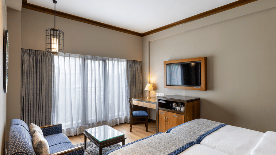 Executive Room with a bed, seating area and wall mounted television at Kenilworth Hotel, Kolkata.