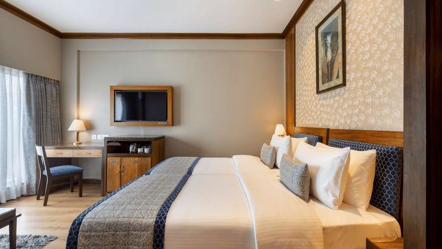 Executive Room with a bed, armchair and wall mounted television at Kenilworth Hotel, Kolkata.