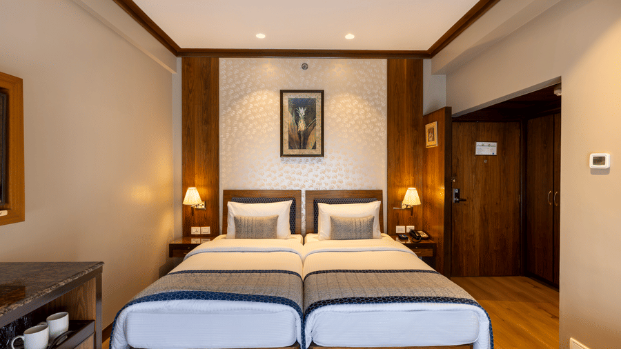 Executive Room with twin beds and framed artwork above the headboards at Kenilworth Hotel, Kolkata.