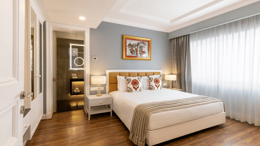 Junior Suite with a bed and framed artwork near the room entrance at Kenilworth Hotel, Kolkata.