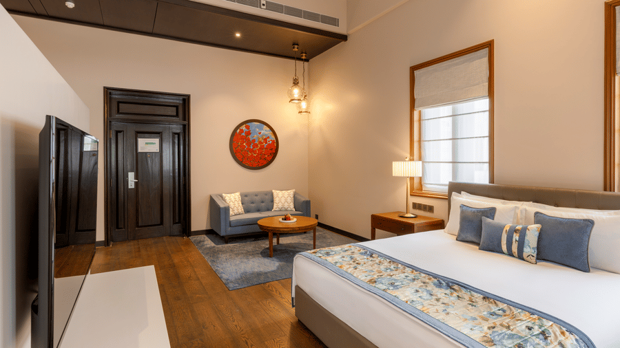 Premier Club Suite with a bed, seating area and wall mounted television at Kenilworth Hotel, Kolkata.