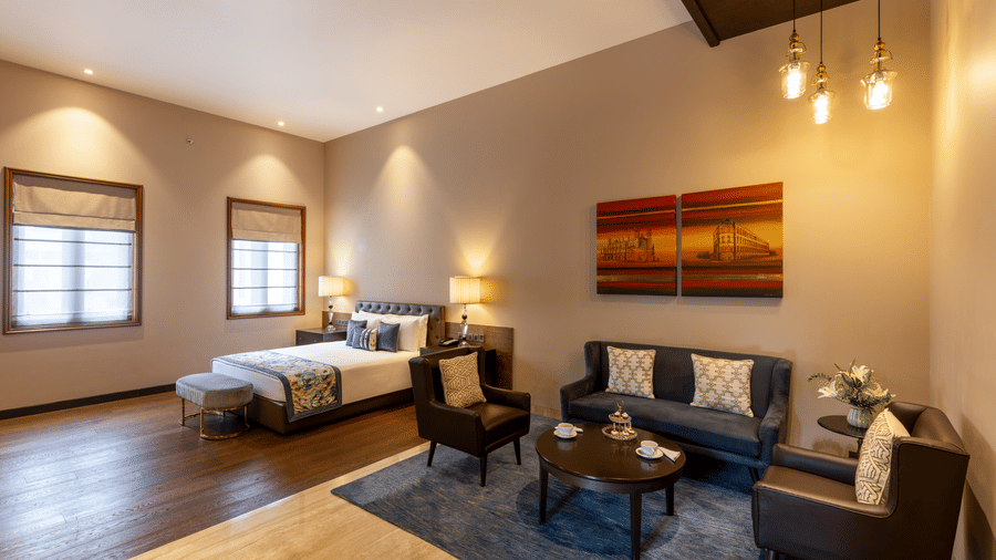 Premier Club Suite with a lounge seating area and bed in the background at Kenilworth Hotel, Kolkata.