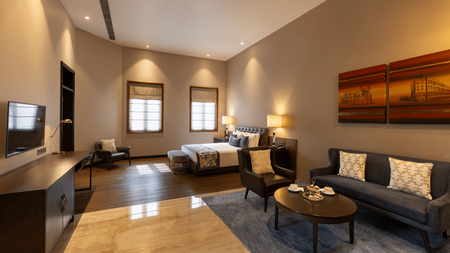 Premier Club Suite with a bed, lounge seating and television unit at Kenilworth Hotel, Kolkata.