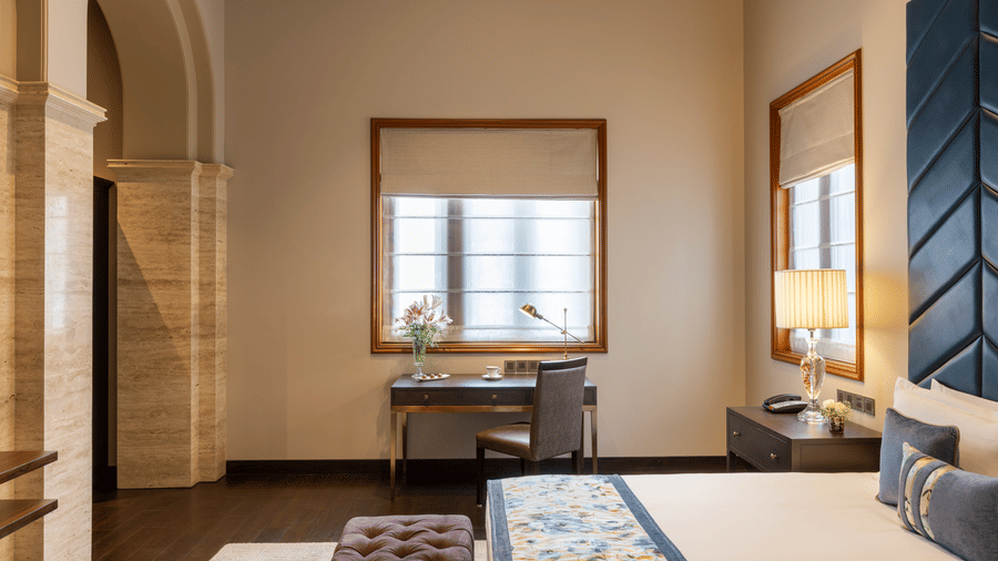 Presidential Suite bedroom with a bed and an arched window with drapes at Kenilworth Hotel, Kolkata.