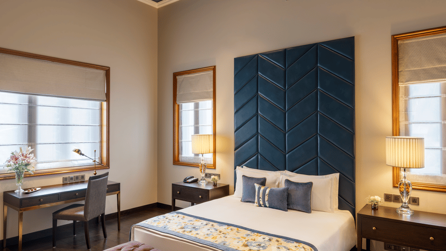 Presidential Suite bedroom with a bed featuring a tall blue headboard at Kenilworth Hotel, Kolkata.