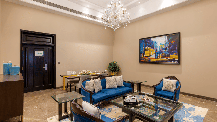 Presidential Suite lounge area with blue sofas and a chandelier at Kenilworth Hotel, Kolkata.