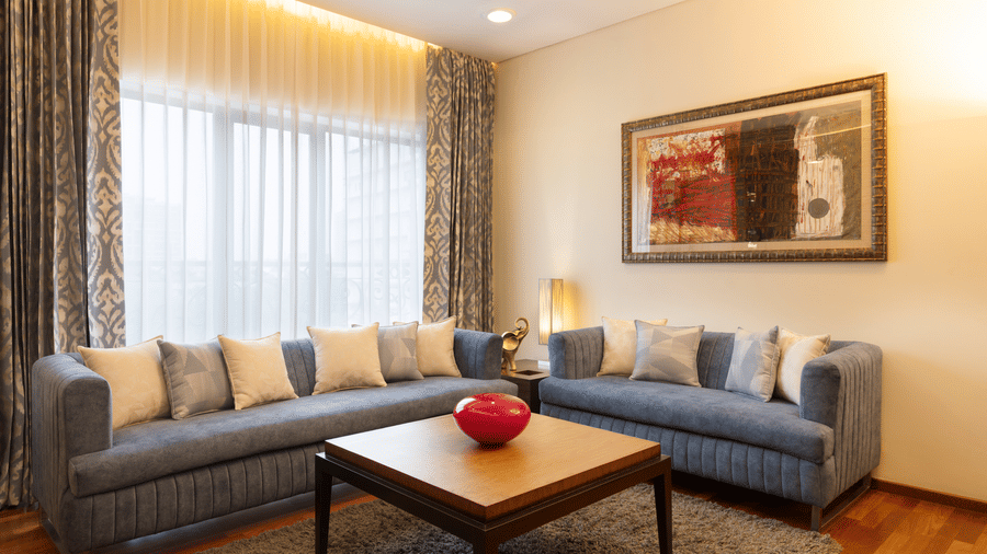 Russel Suite lounge area with a blue sofa and framed artwork at Kenilworth Hotel, Kolkata.