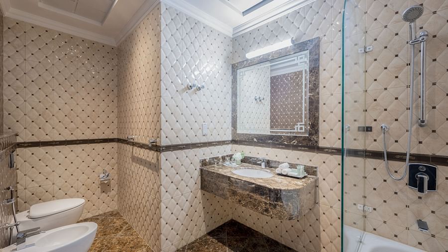 An elegant washroom with a bathtub and a sink in view - La Maison Hotel, Doha