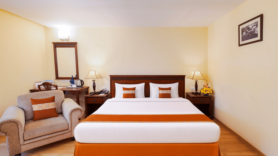 A room with a large bed, spreads, pillows, a sofa, a mirror, and lights. | MGM Mark Whitefield