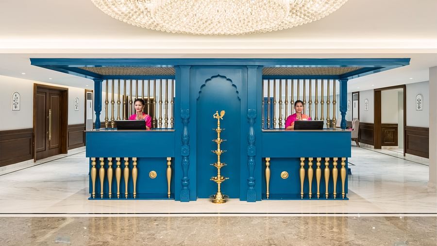 An image of our reception hall at our hotel with a blue reception desk and two receptionists standing behind it - MJ Sarovar Portico, Haridwar