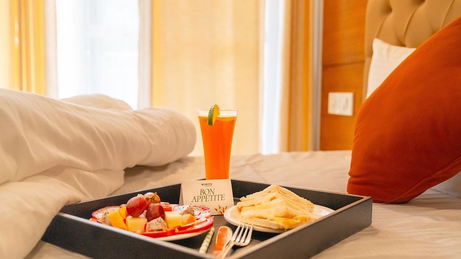A breakfast platter placed on a bed at  Montclair Ananta, Elite.