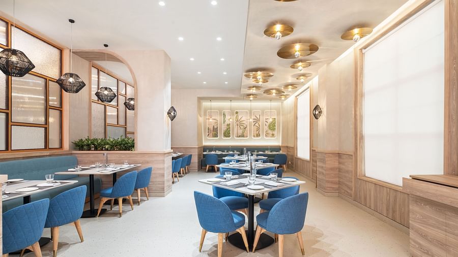 A restaurant interior with a long dining table and a plant wall.
