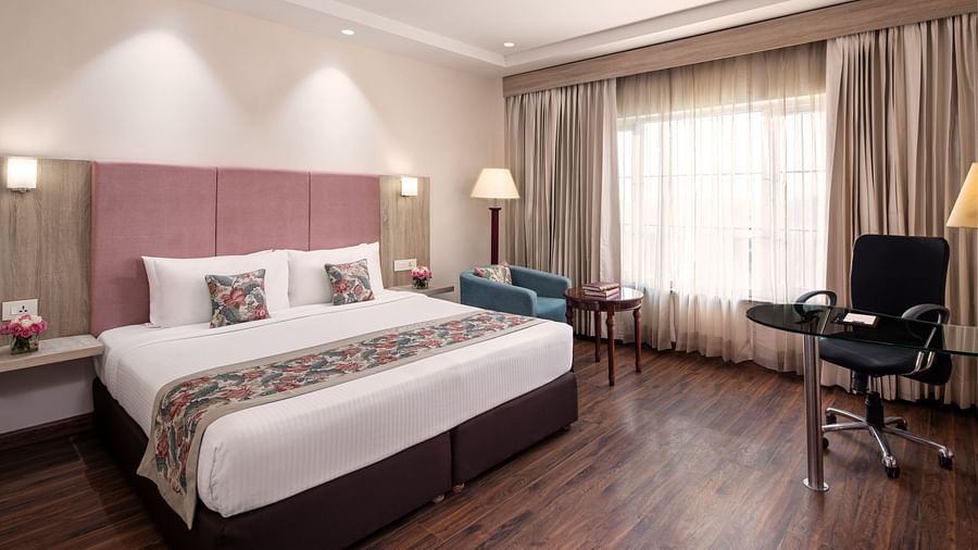 A hotel bedroom with a bed, a seating area, and a TV.