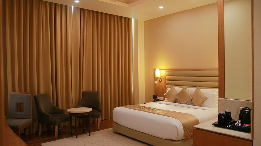 Image of room under warm lighting featuring a plush bed and couches with coffee table next to the window