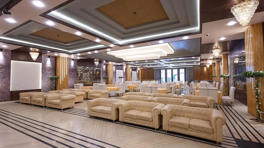 A grand hotel lobby or banquet hall featuring comfortable white sofas and a high, decorative ceiling - Pride Premier Dehradun