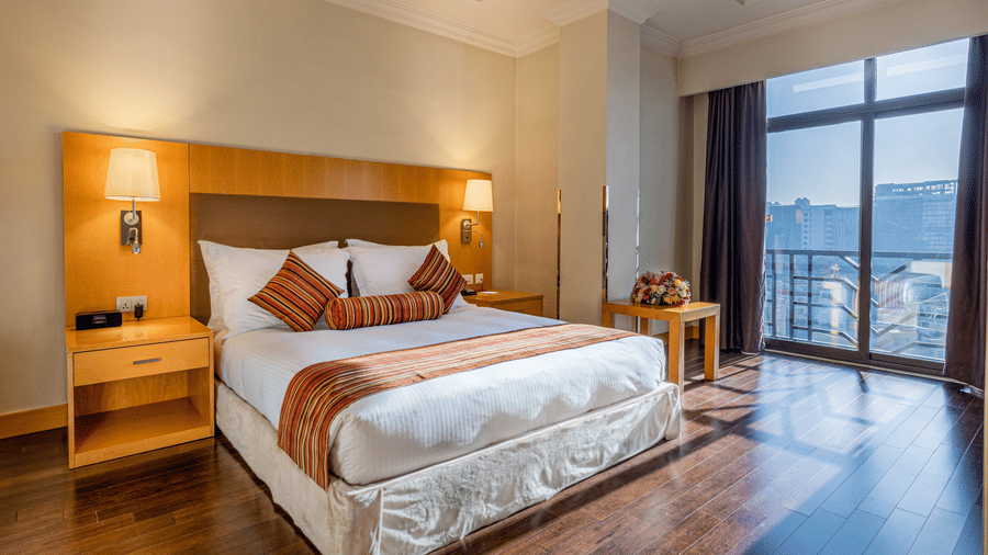 Executive Suite at Ramada by Wyndham Addis, one of the best places to stay in Addis Ababa, featuring a plush king size bed with striped cushions under warm lighting, and large windows with city views