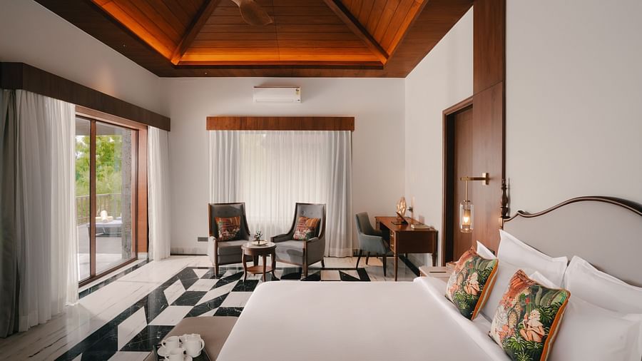 A side view of the room at The Ananta Udaipur with a king sized bed, a flat-screen TV, and a window with the view.