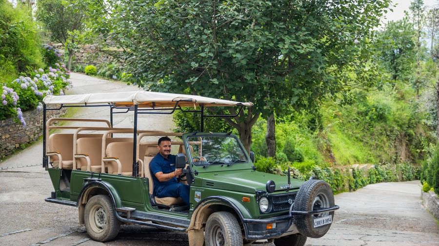 Guest arriving in an open jeep surrounded by greenery, illustrating adventure activities offered at The Manor Sports & Wellness Hotel, Shimla.