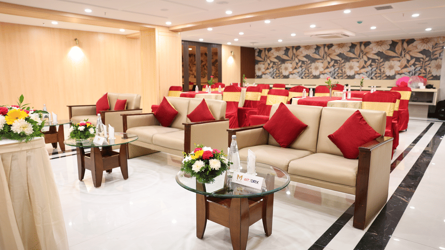 A lounge style event setup in Coronet Ball Room at The Monarch Hotel, Brigade Road featuring sofas arranged in rows with centre tables and aisle space.