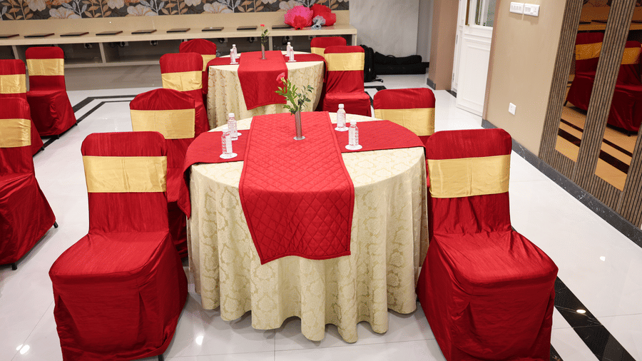 A round table dining setup in Coronet Ball Room at The Monarch Hotel, Brigade Road with covered chairs and table settings for a formal function.