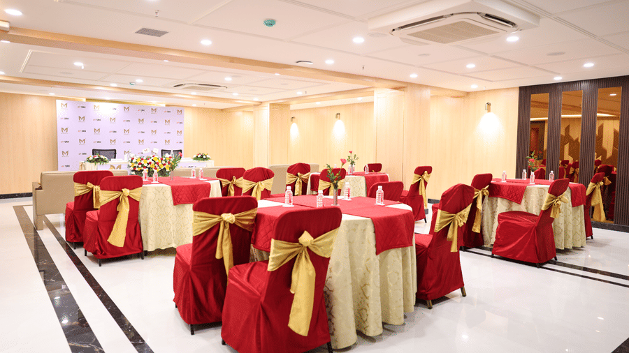 A wide interior view of Coronet Ball Room at The Monarch Hotel, Brigade Road showing multiple round tables ceiling lighting and open floor space.