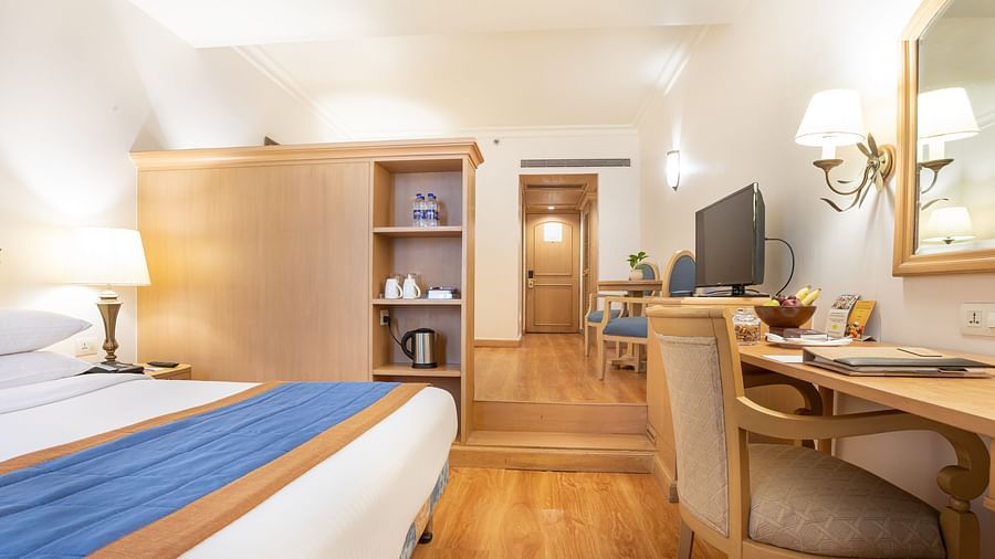 Room with a bed, wardrobe, television and work desk chair - The Orchid Hotel Mumbai Vile Parle