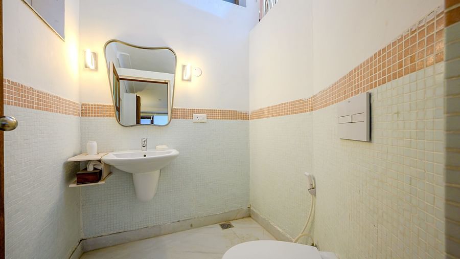 Bathroom with sink, mirror, wall lighting, toilet, and tiled floor - Tijara Fort-Palace - 19th Century, Alwar.