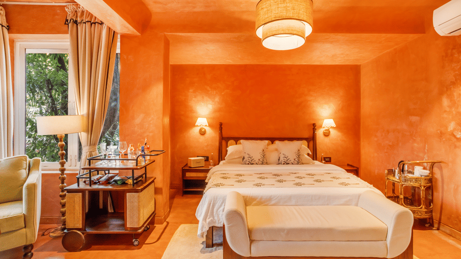 Bright bedroom at Unseen Boutique Hotel featuring cushioned bench, bedside lamps, and warm decor for a cheerful and cosy atmosphere.