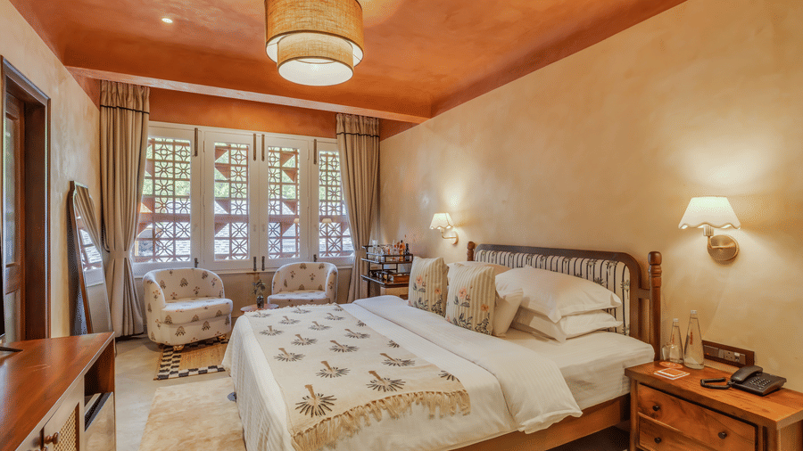 Bedroom at Unseen Boutique Hotel with large bed, patterned bedding, standing mirror, and warm earthy walls.